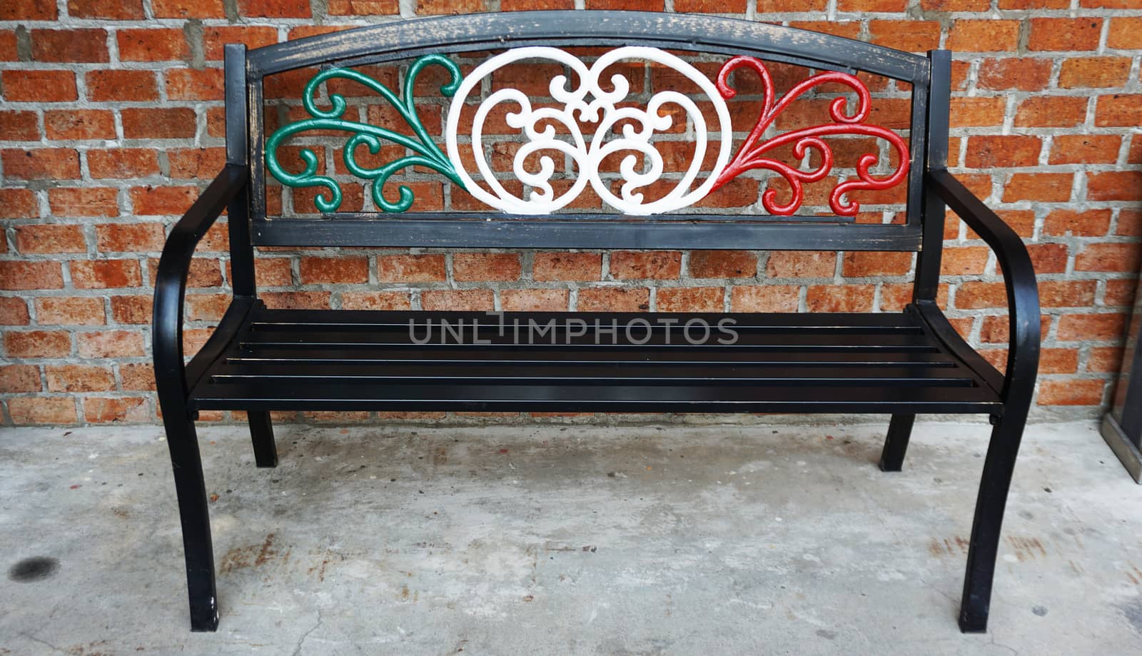 An iron bench chair draped in Italian flag colors outside of an Italian restaurant . Metal bench furniture for people waiting outside the restaurant.