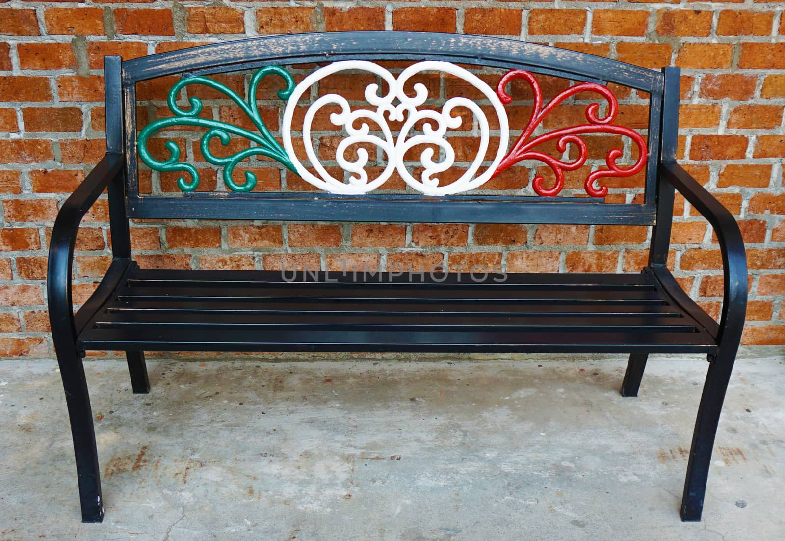 An iron bench chair draped in Italian flag colors outside of an Italian restaurant . Metal bench furniture for people waiting outside the restaurant.