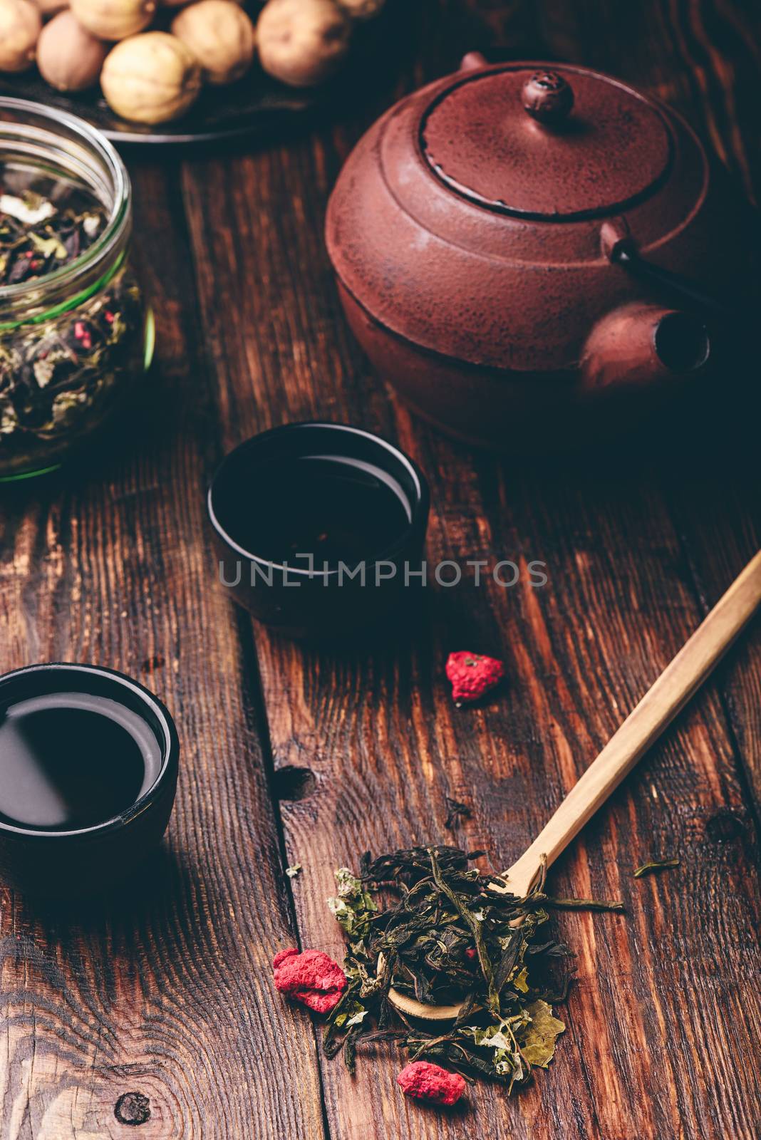 Cast iron tea bowls with teapot and wooden spoonful of raspberry herbal tea