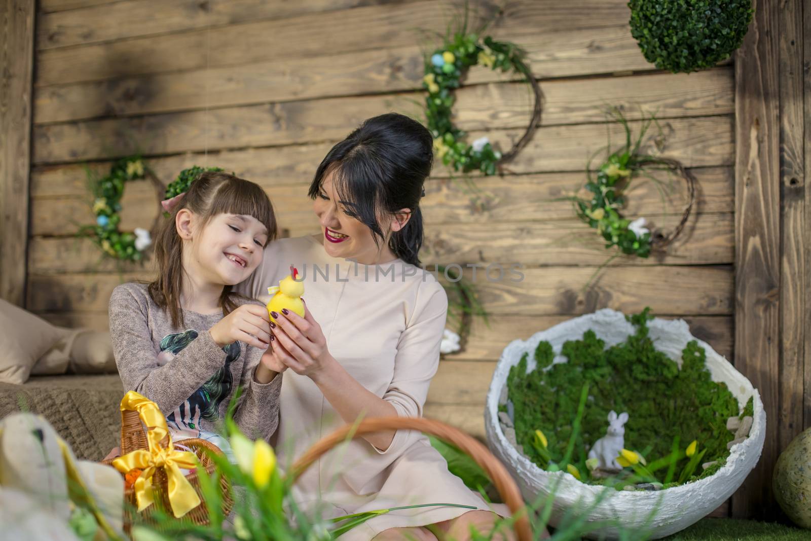 Mother and daughter with Easter eggs in decorated studio