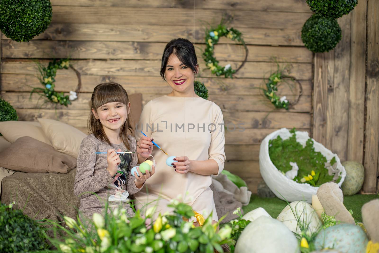 Mother and daughter with Easter eggs in decorated studio