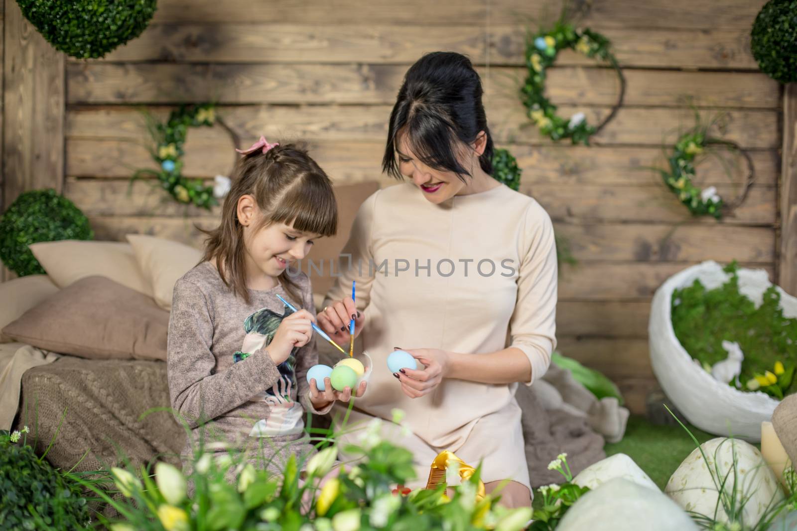 Mother and daughter with Easter eggs in decorated studio by Angel_a