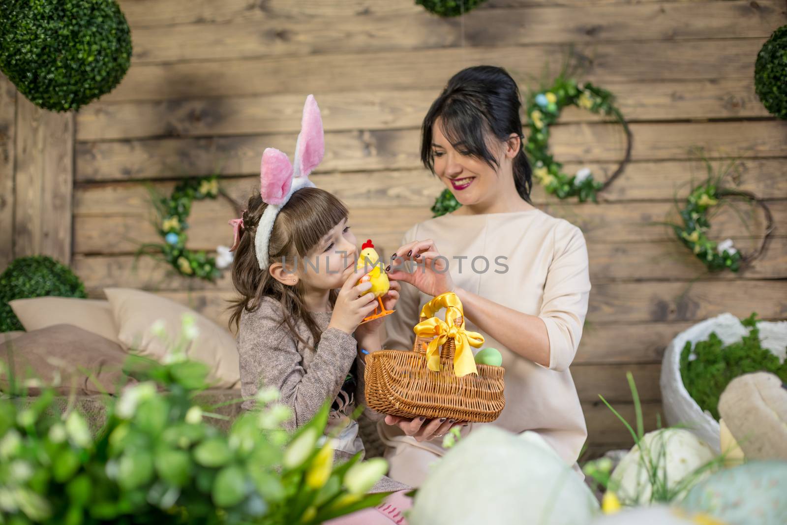 Mother and daughter with Easter eggs in decorated studio