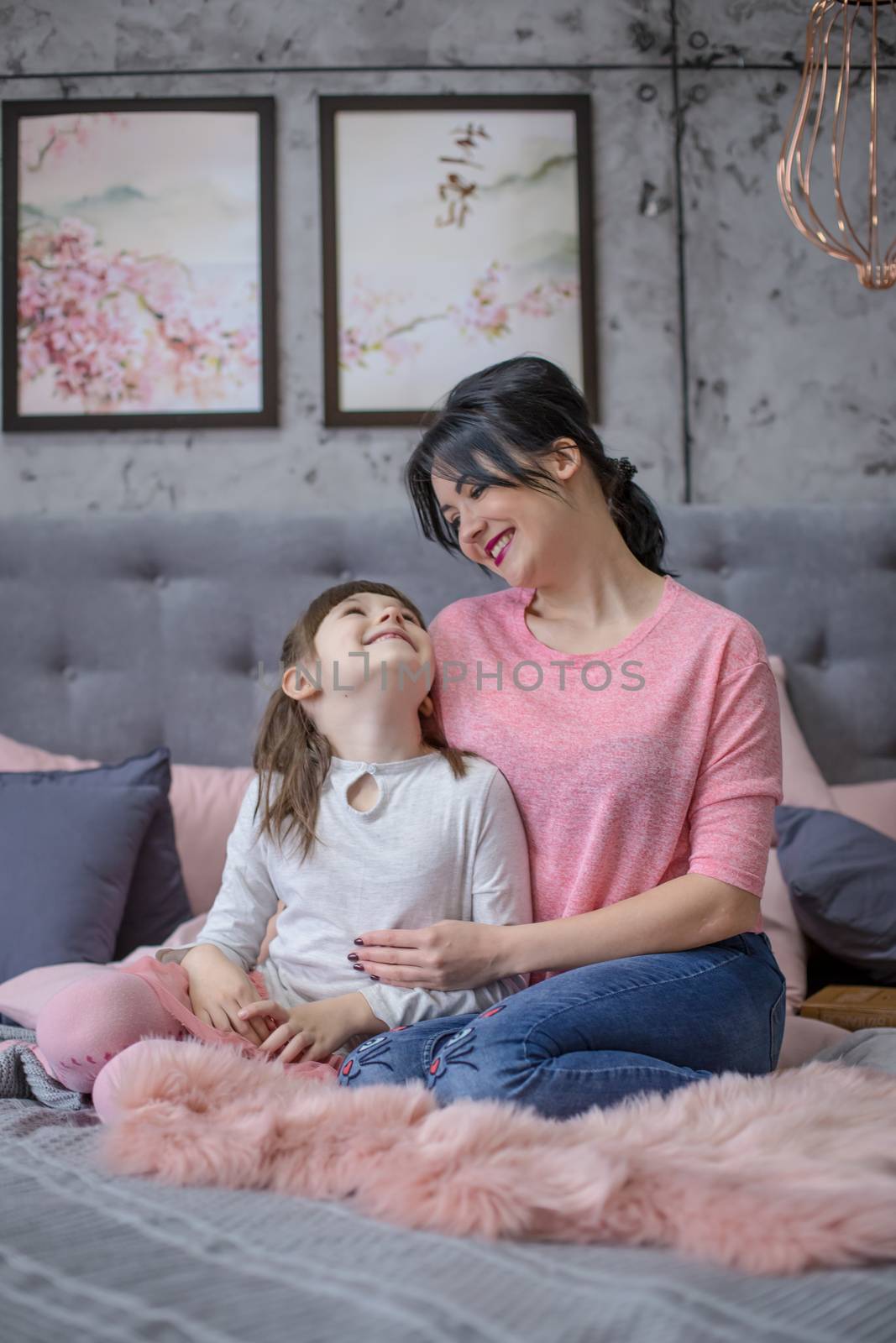 Mother and child daughter play and hug in bed by Angel_a