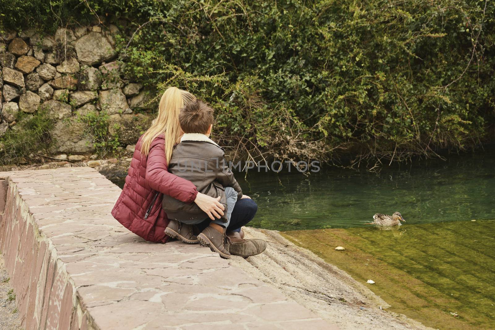 Mother and son watching the water raft with ducks. Colors of nature