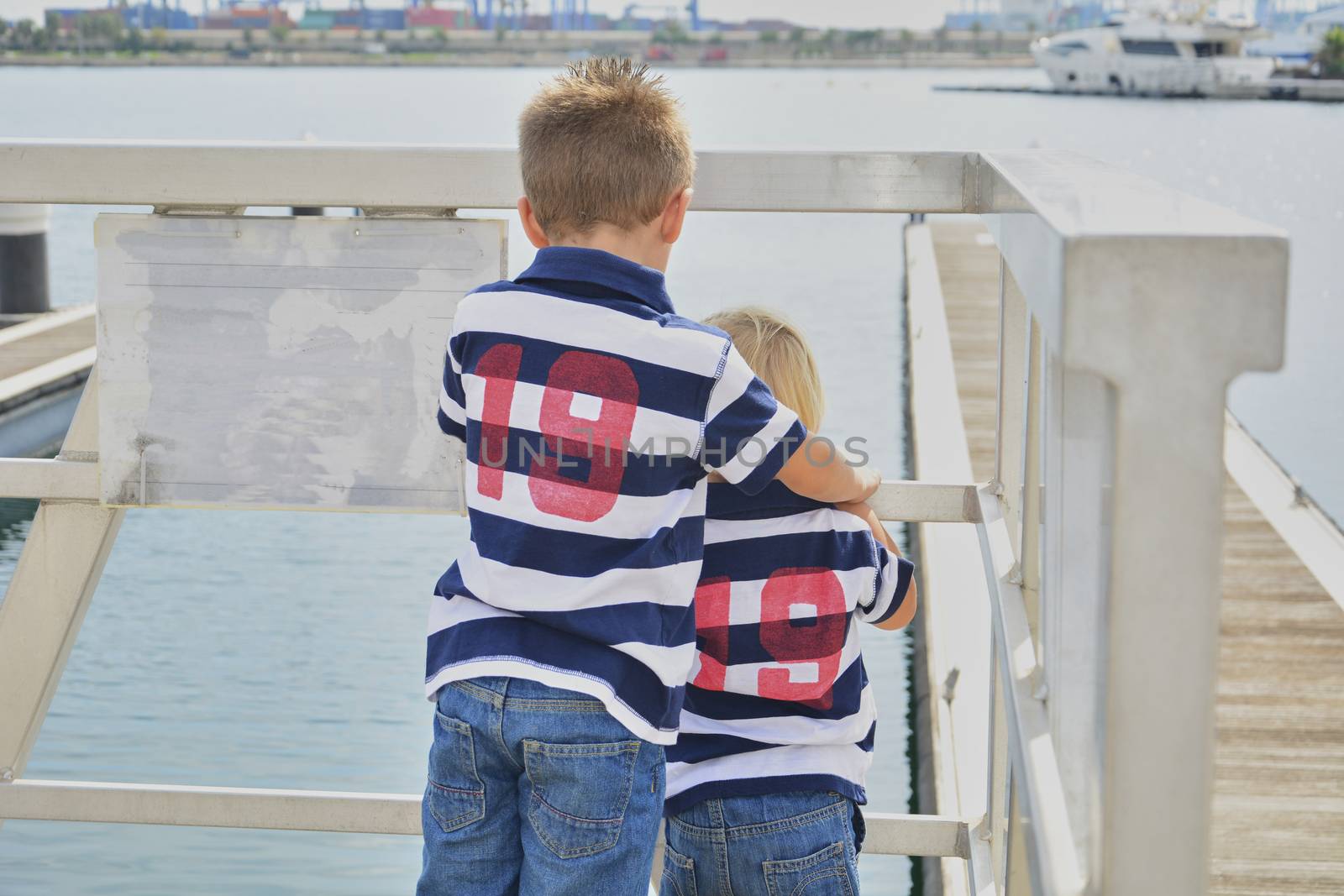 Two children looking through a fence at the sea, Friendship and love