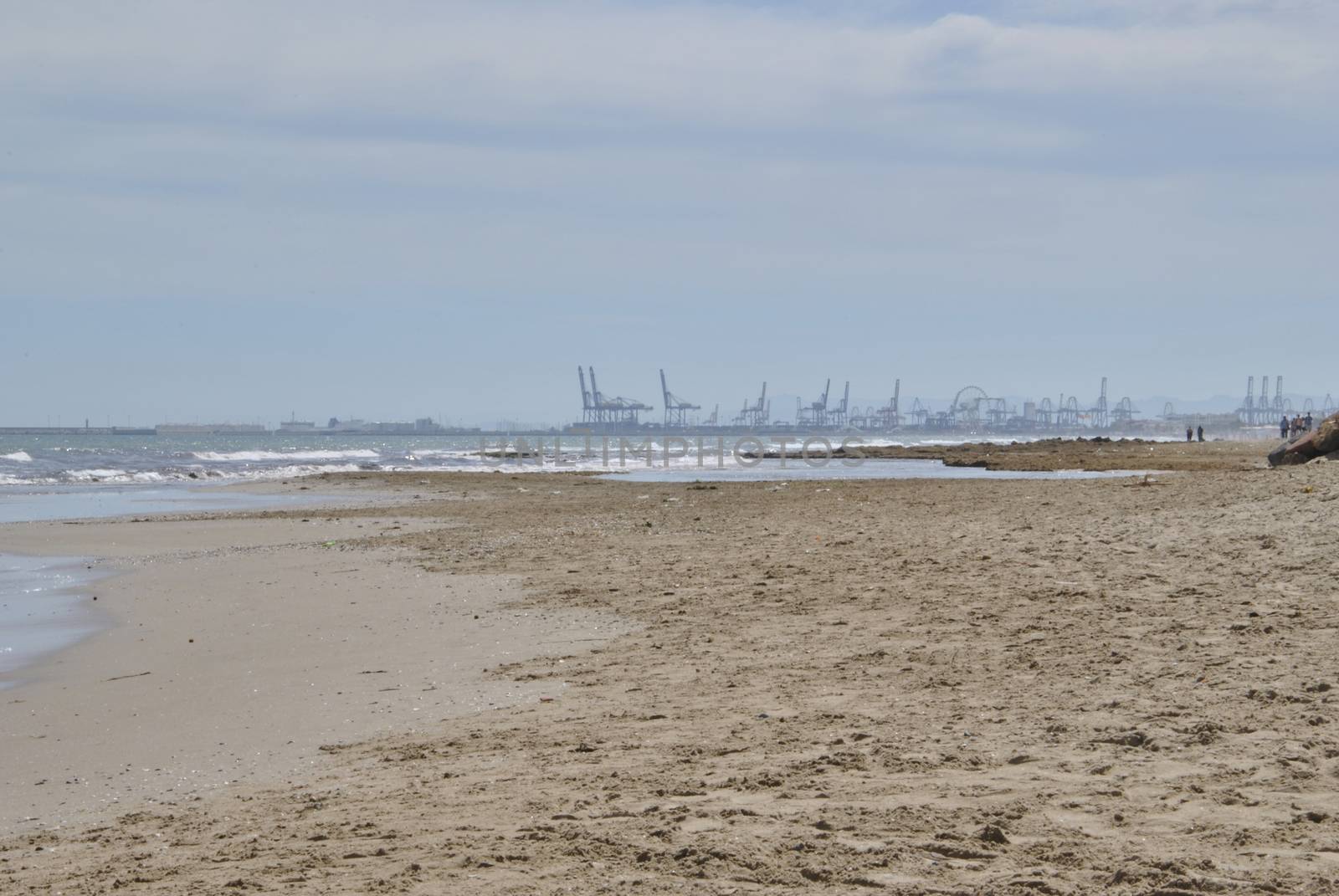 The port cranes seen from the beach. Machine colors