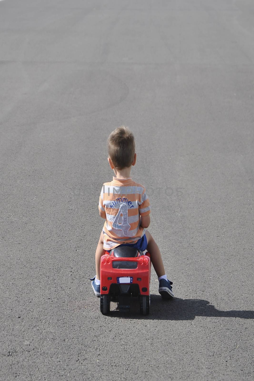 Boy in striped shirt playing with toy car. Colors of persons