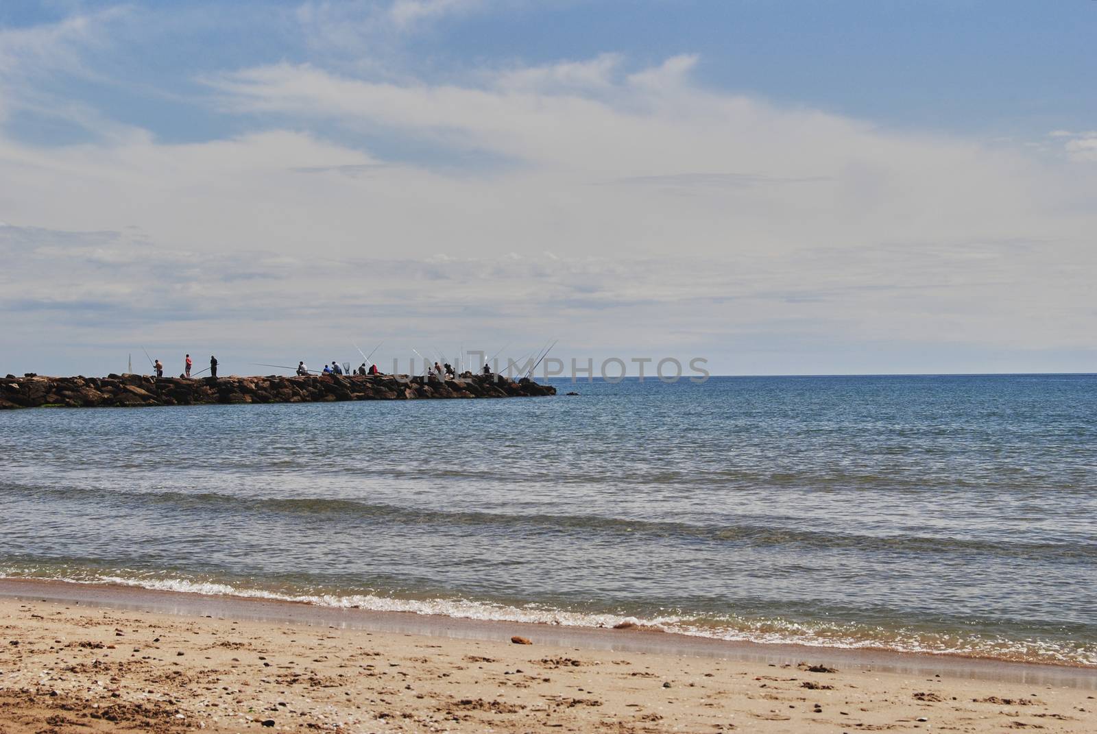 People fishing in the groynes on a bright day. Colors of nature