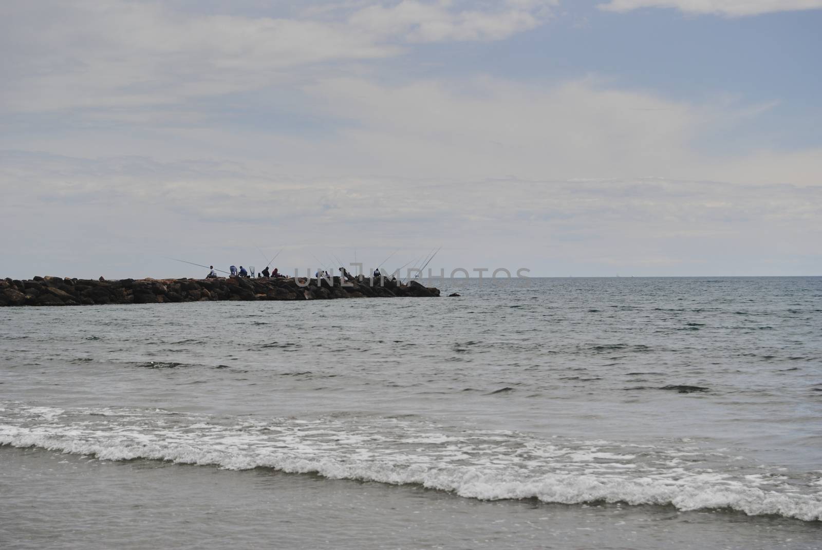 People fishing in the groynes on a bright day. Colors of nature