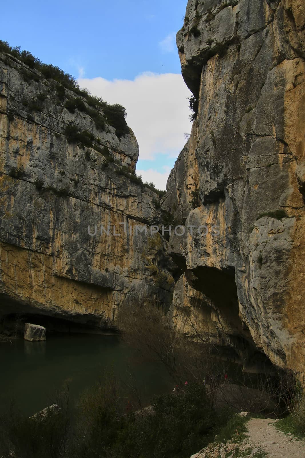 River through steep mountains, Bluish sky with soft white clouds