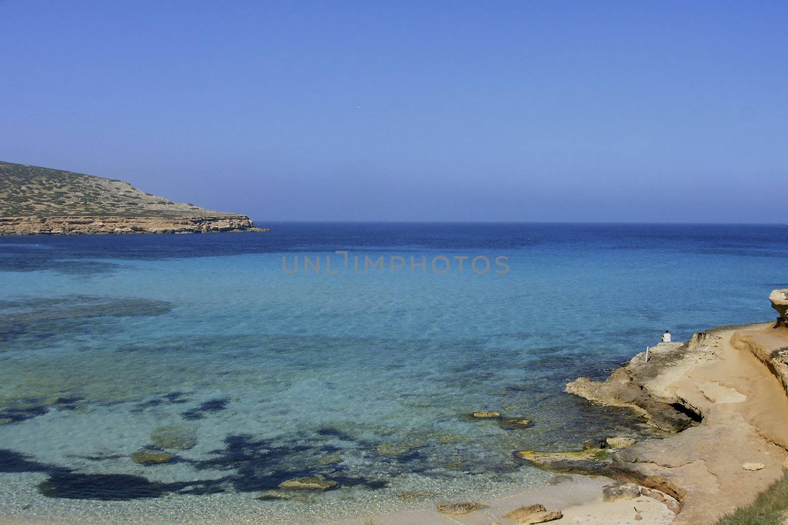 Deserted beach with turquoise waters, bright day, Mountains in the background and bright blue day,