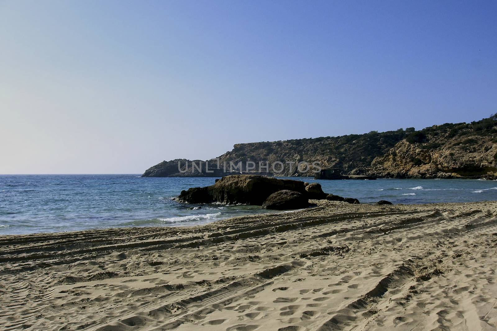 Deserted beach with turquoise waters, bright day, Mountains in the background and bright blue day,