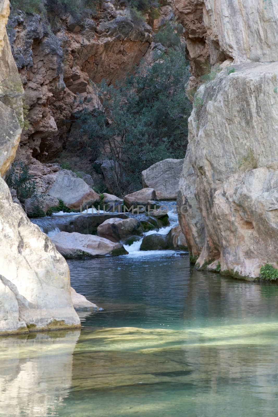 River of calm waters between two mountains, transparent waters, small waterfall