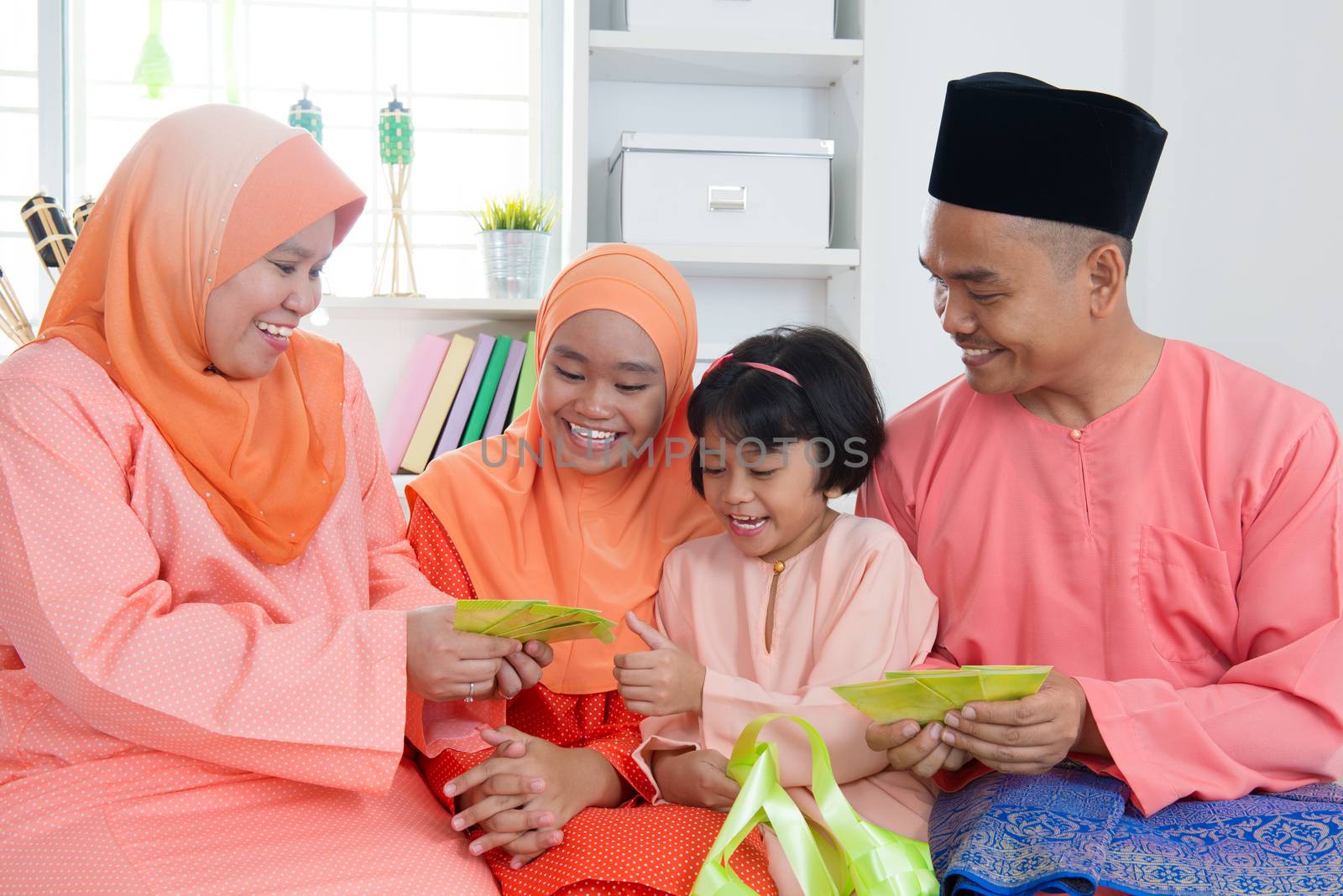 Woman giving green packet to the girls during hari raya. Malay or Malaysian family lifestyle at home.