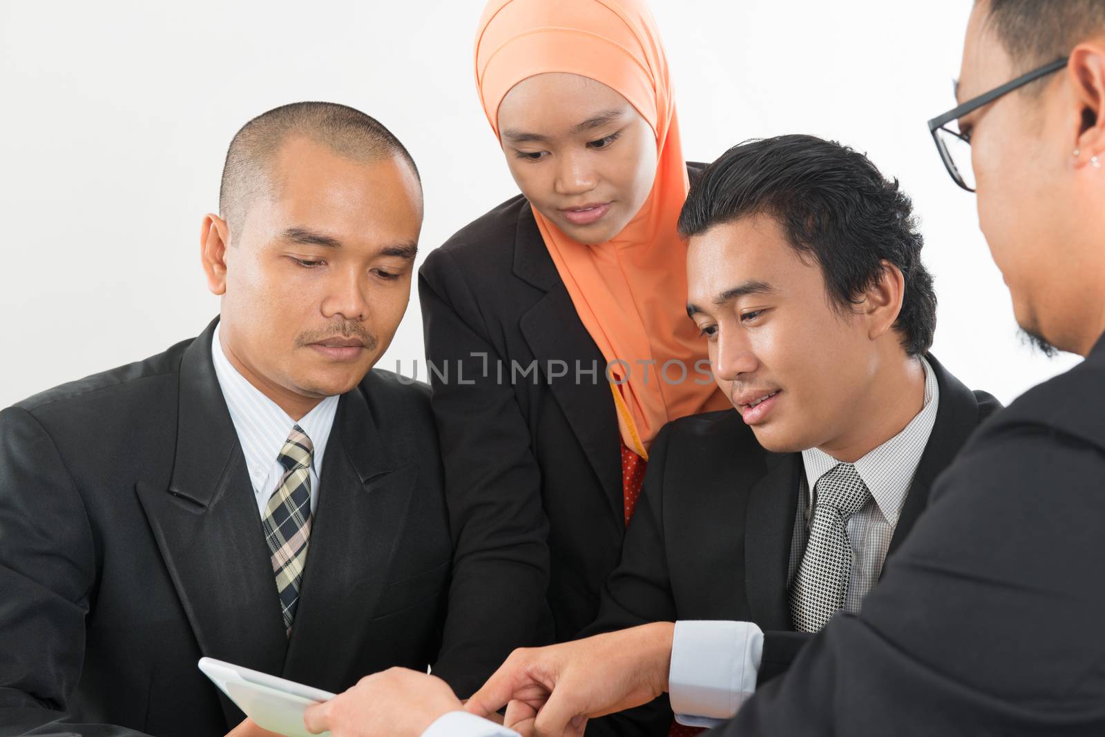 Group of Malaysian businesspeople meeting or having discussion on desk inside office room.