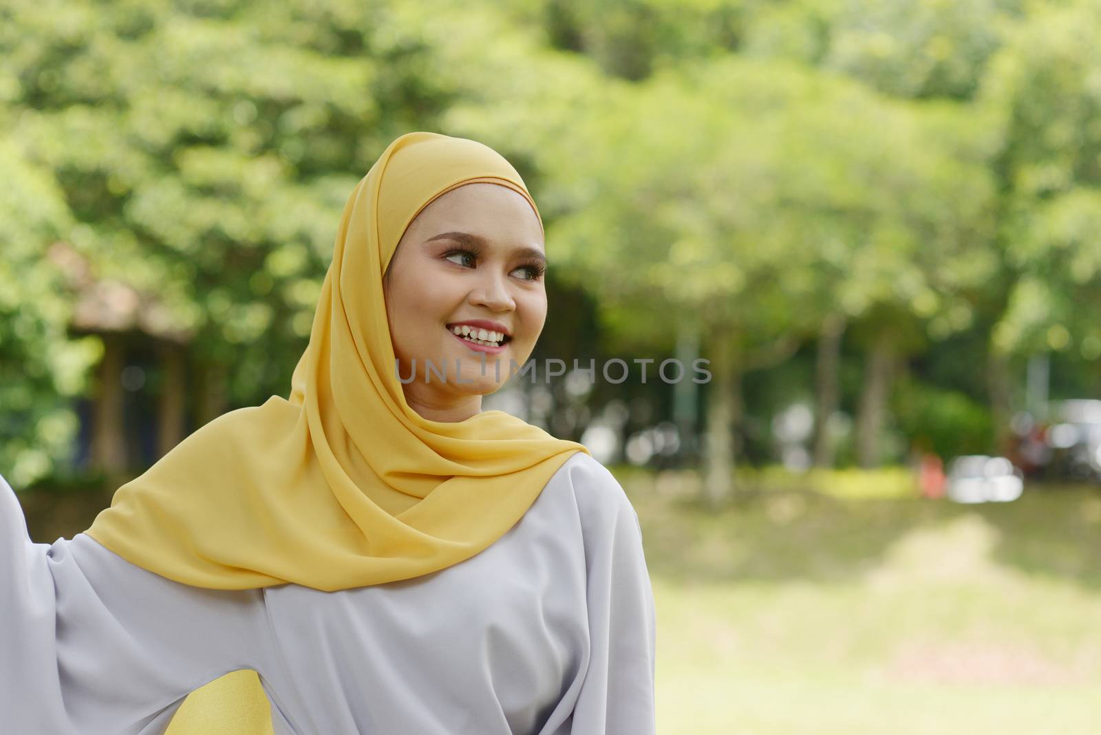 Portrait of cheerful Muslim girl in hijab, smiling at outdoor.