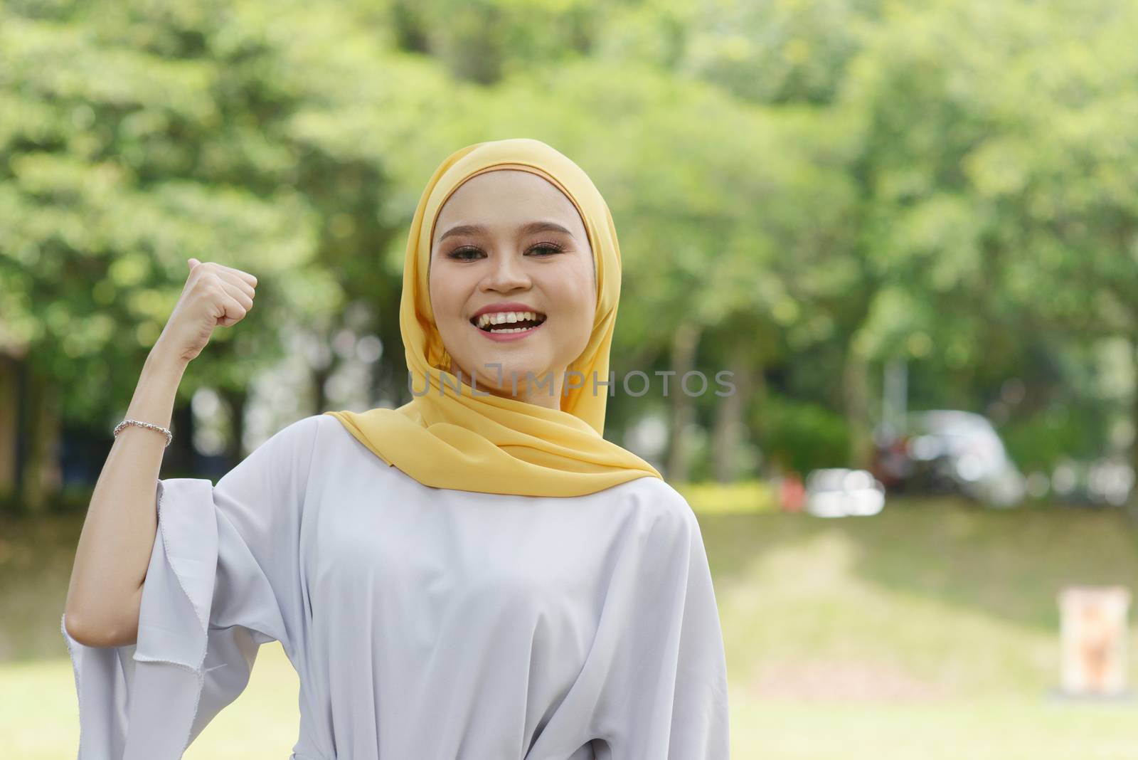 Portrait of cheerful Muslim girl thumb up, smiling at outdoor.