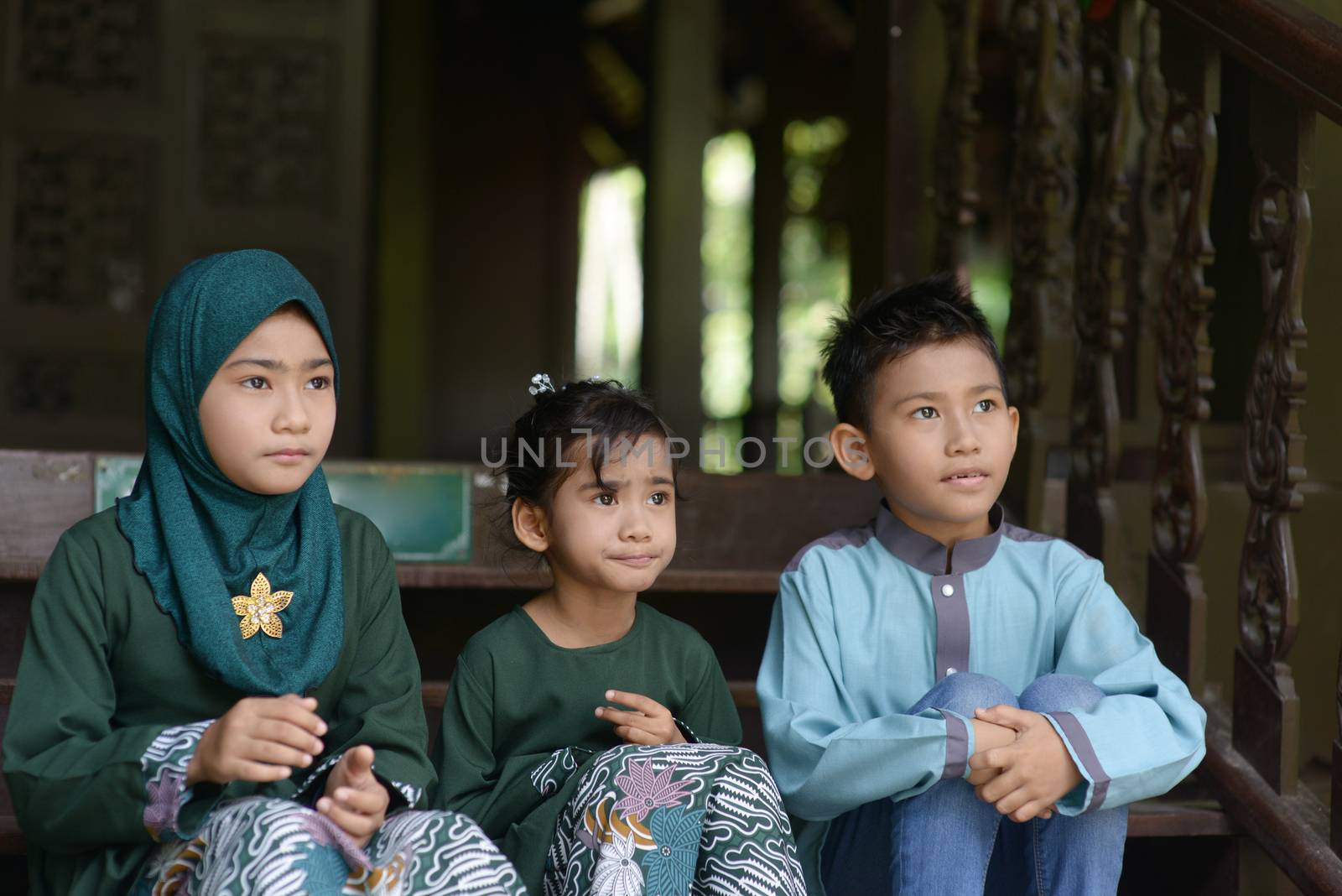 Muslim children sitting and looking away, Hari raya eid al-fitr concept. 