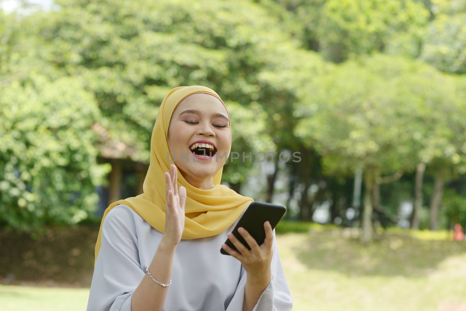 Cheerful Muslim girl using smartphone by szefei