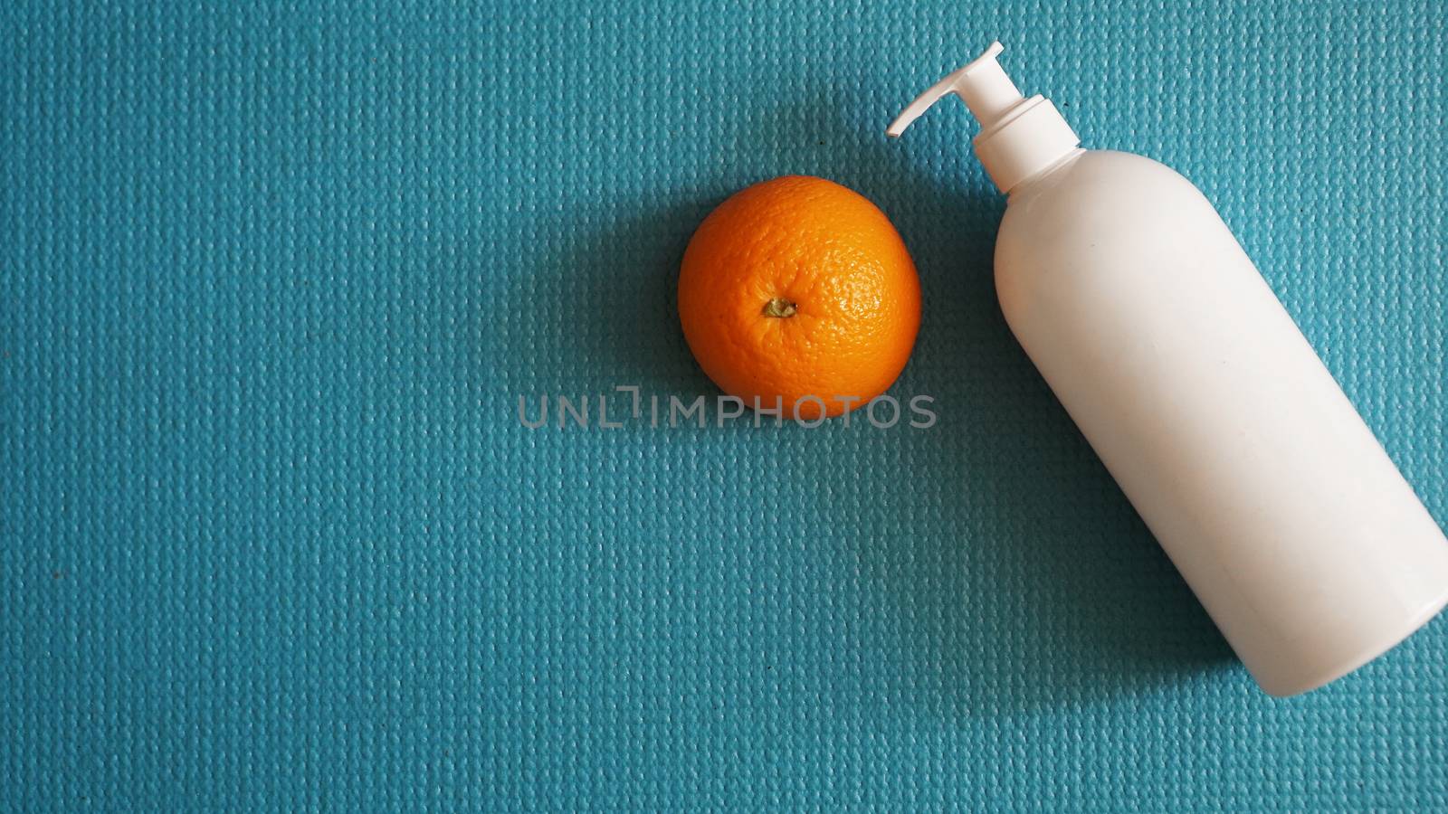 Lotion and orange fruit - anti-cellulite concept on a blue background