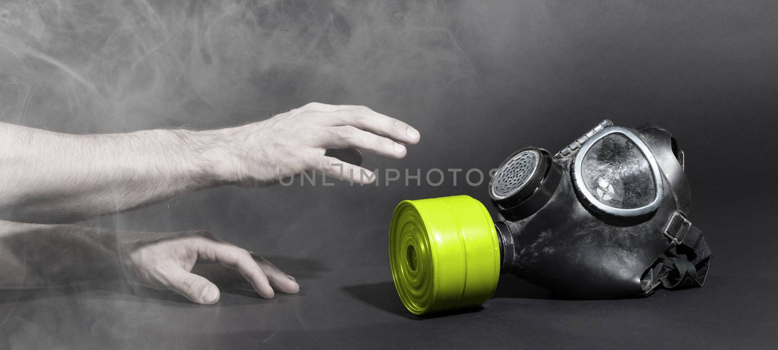 Man in room filled with smoke, trying to reach for vintage gasmask - Isolated on black - Green filter