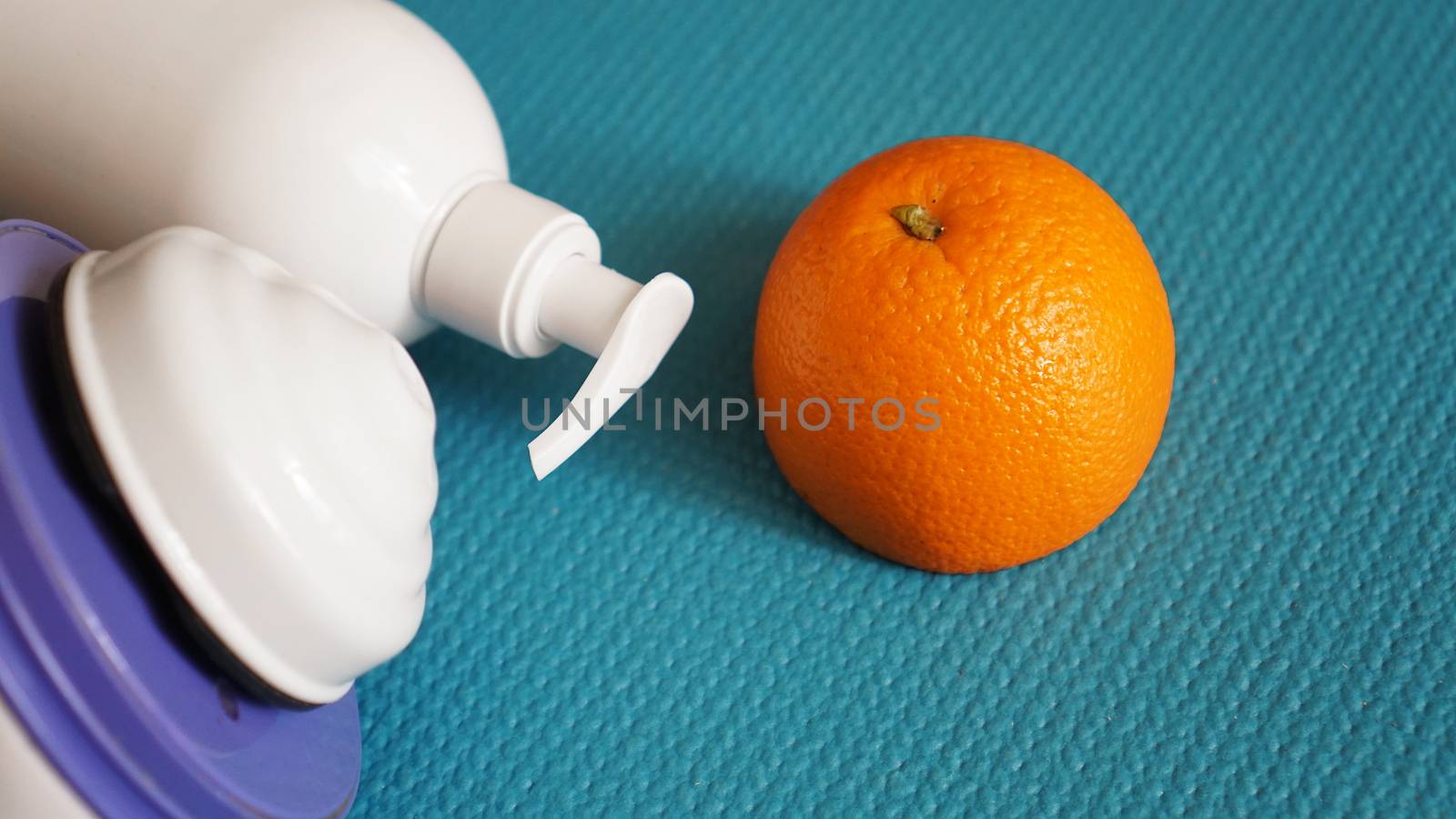 Electric massager for cellulite. Lotion, orange and anti-cellulite massage massager on a blue background