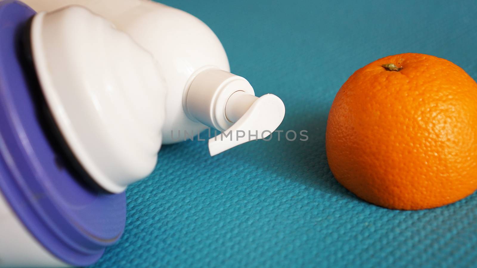 Electric massager for cellulite. Lotion, orange and anti-cellulite massage massager on a blue background