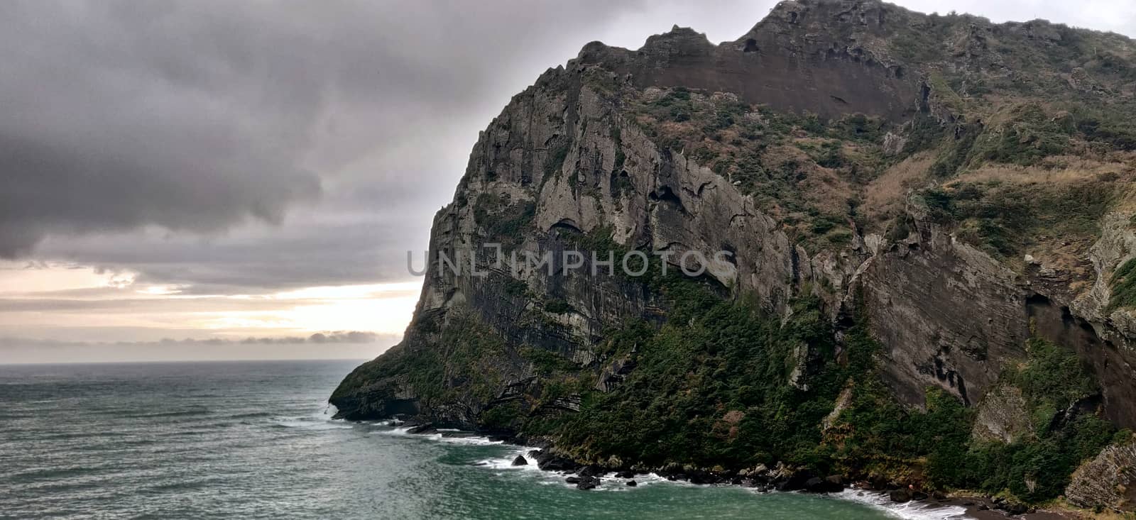 Cliff with green grass on the sea shore on a rainy cloudy day
