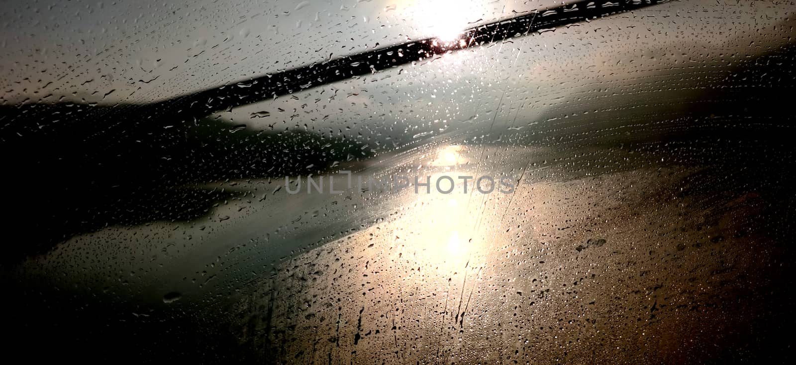 Abstract sunrise seen through dew filled window with reflection in the ocean