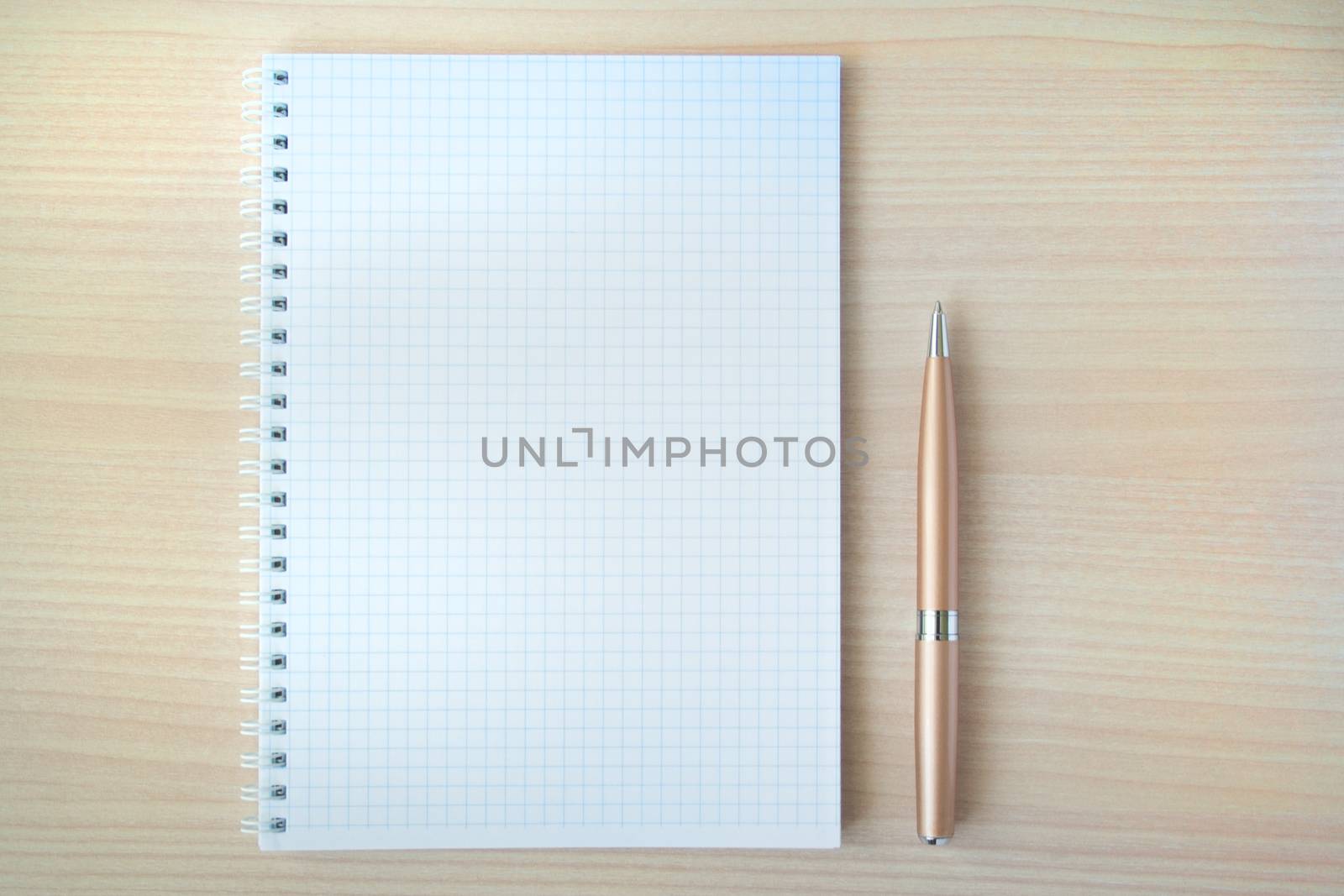 Pen with open clear notepad on wooden table
