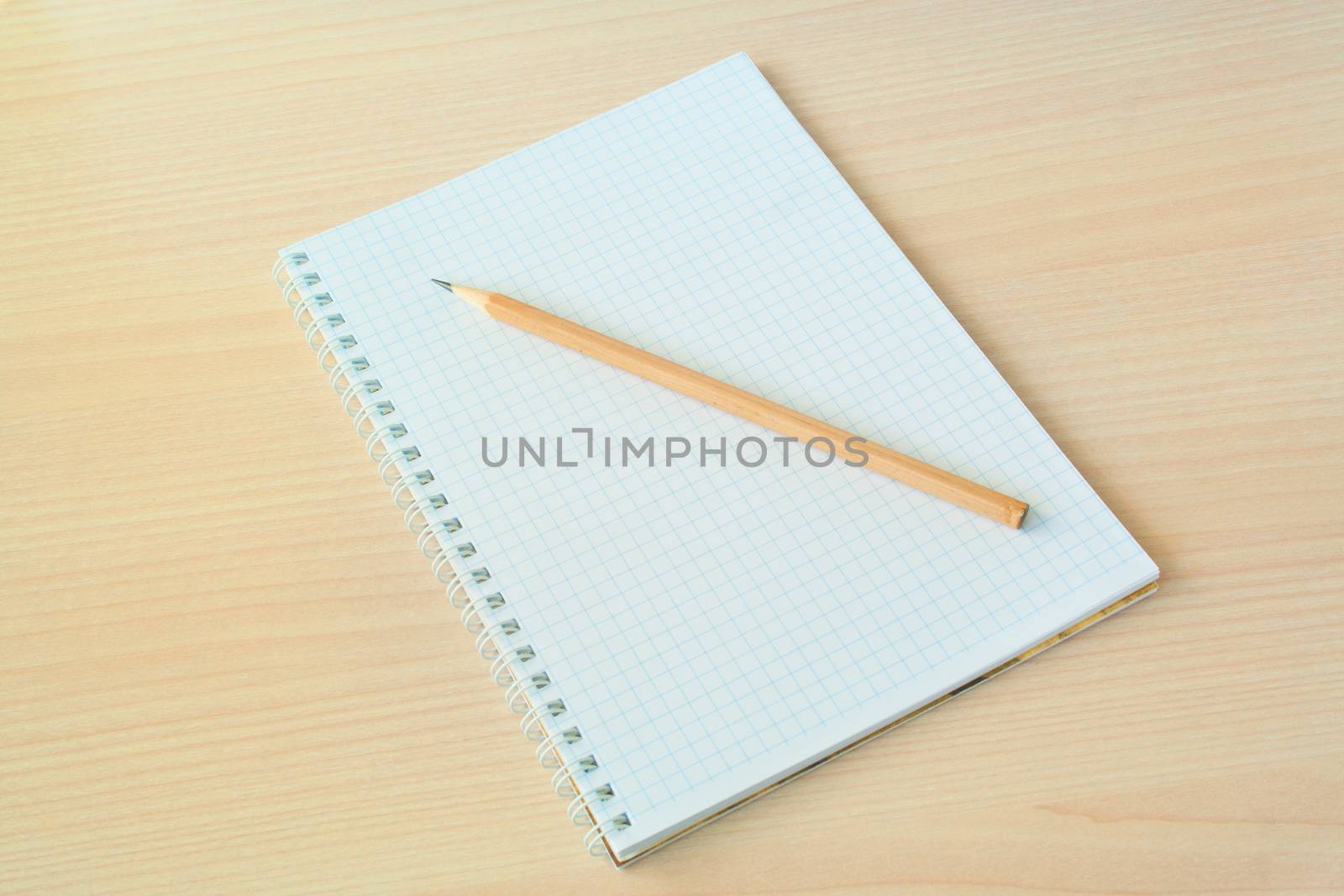 Pencil with open clear notepad on wooden table
