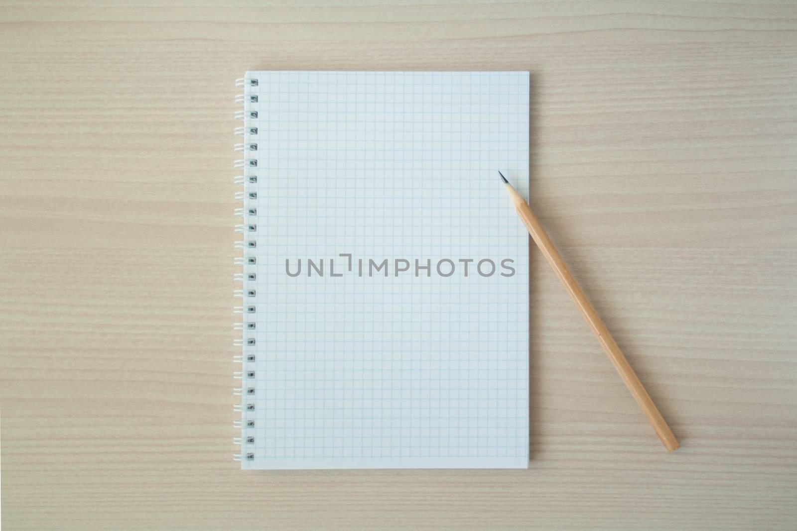 Pencil with open clear notepad on wooden table
