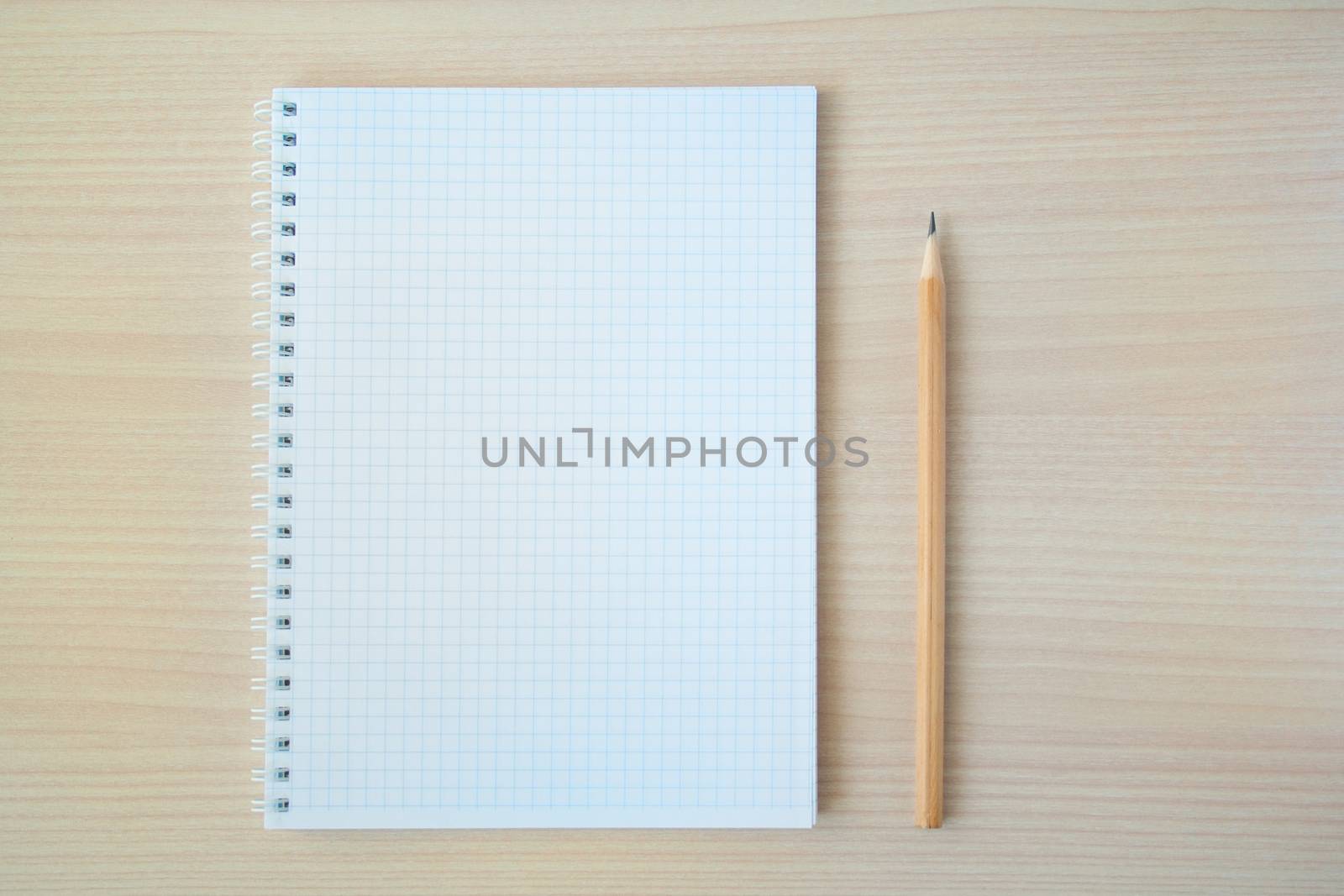 Pencil with open clear notepad on wooden table
