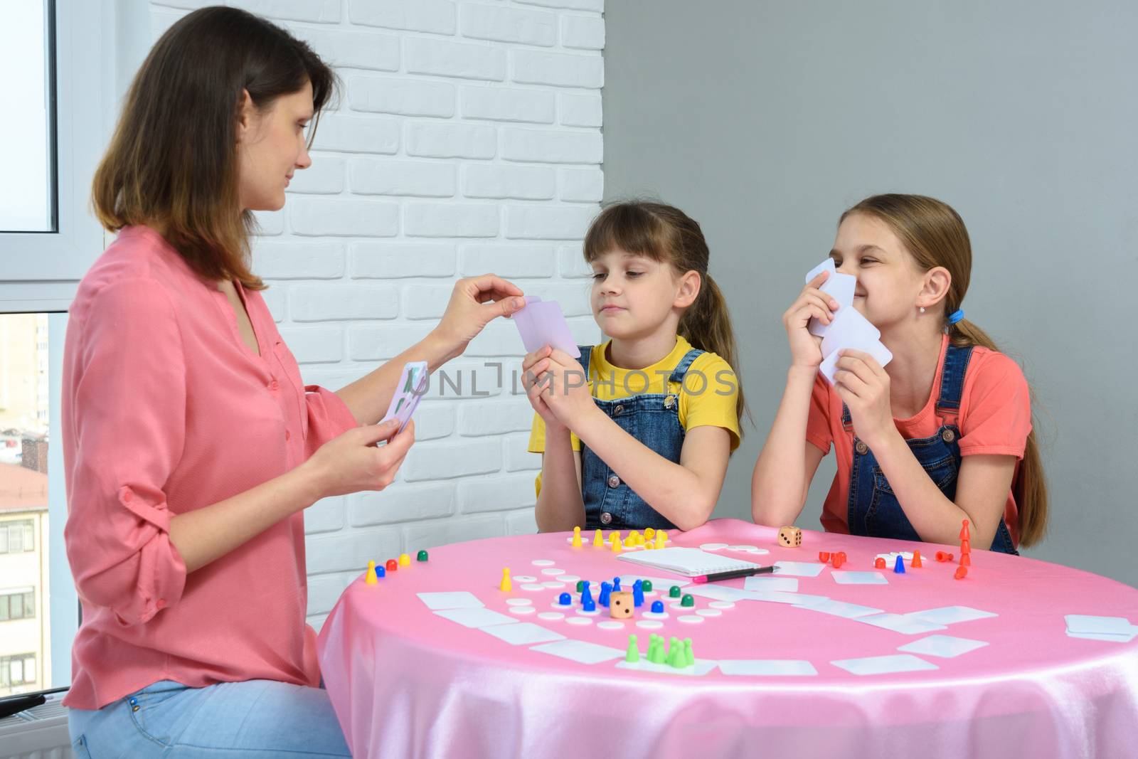 In the process of a board game, mom chooses a card from her daughter's hand