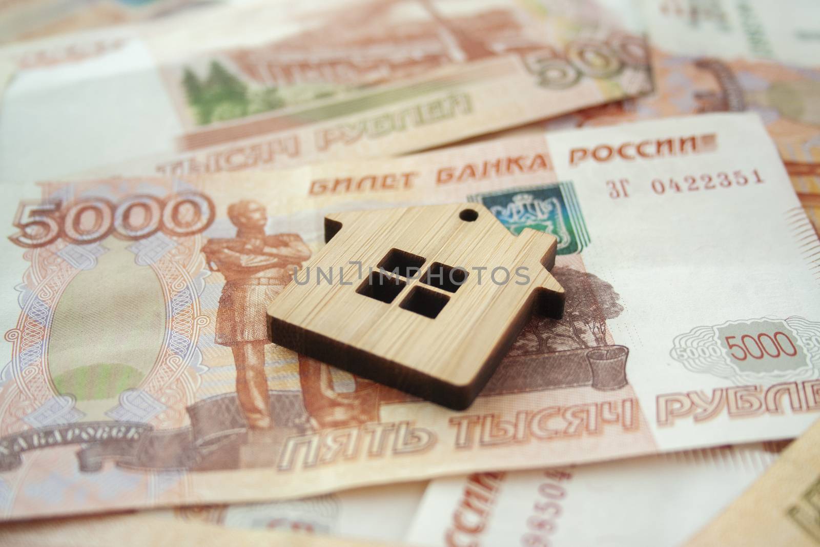 Mortgage, insurance, buying and rent, real estate business concept. Small wooden house toy on money rouble banknotes background side view