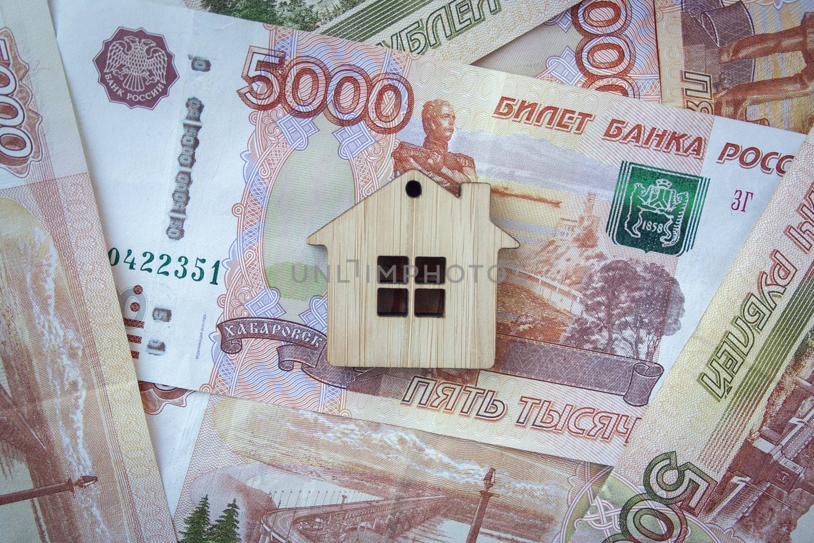 Mortgage, insurance, buying and rent, real estate business concept. Small wooden house toy on money rouble banknotes background top view