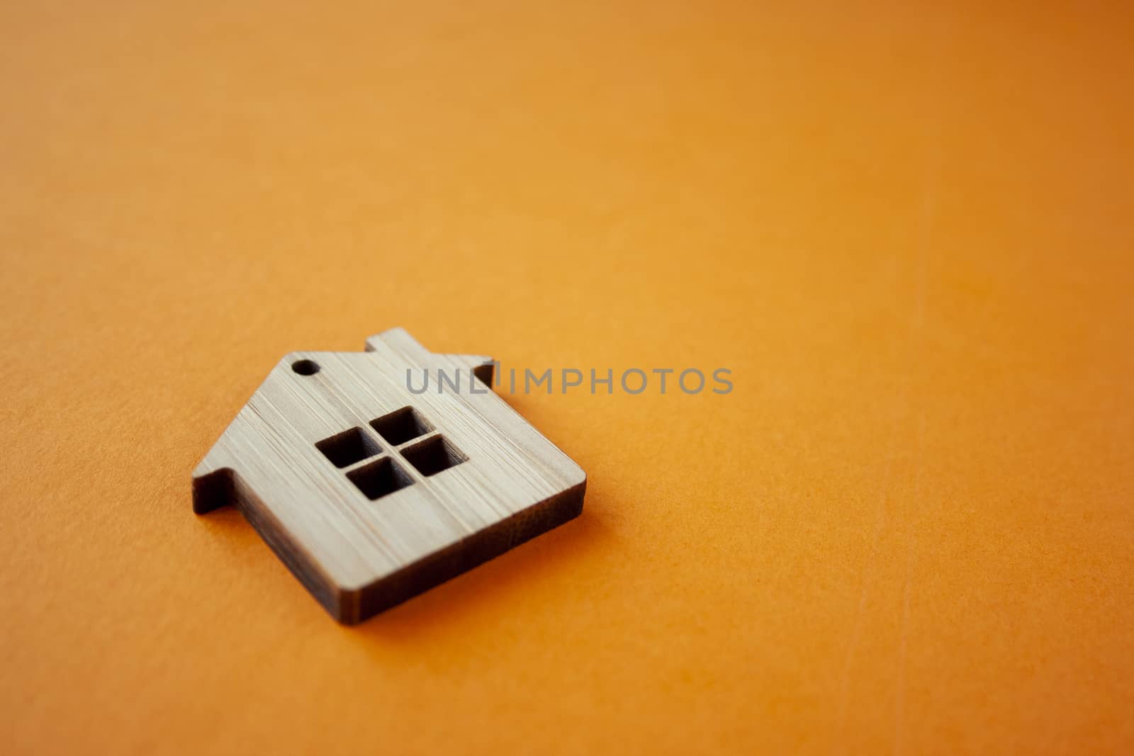 House, insurance and mortgage, buing and rent concept. Small wooden house toy on orange background side view copyspace