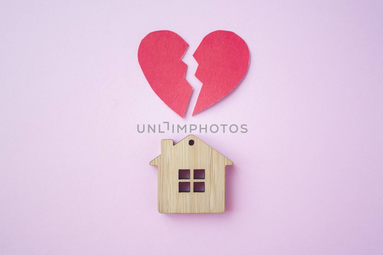 Divorce, division of property, poverty and no money concept. Wooden house with broken heart on bright pink background. Mortgage, rent, realtor
