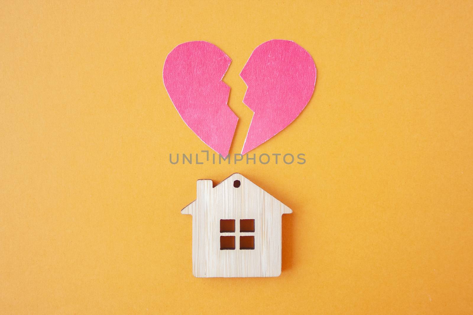 Divorce, division of property, poverty and no money concept. Wooden house with broken heart on bright orange  background. Mortgage, rent, realtor