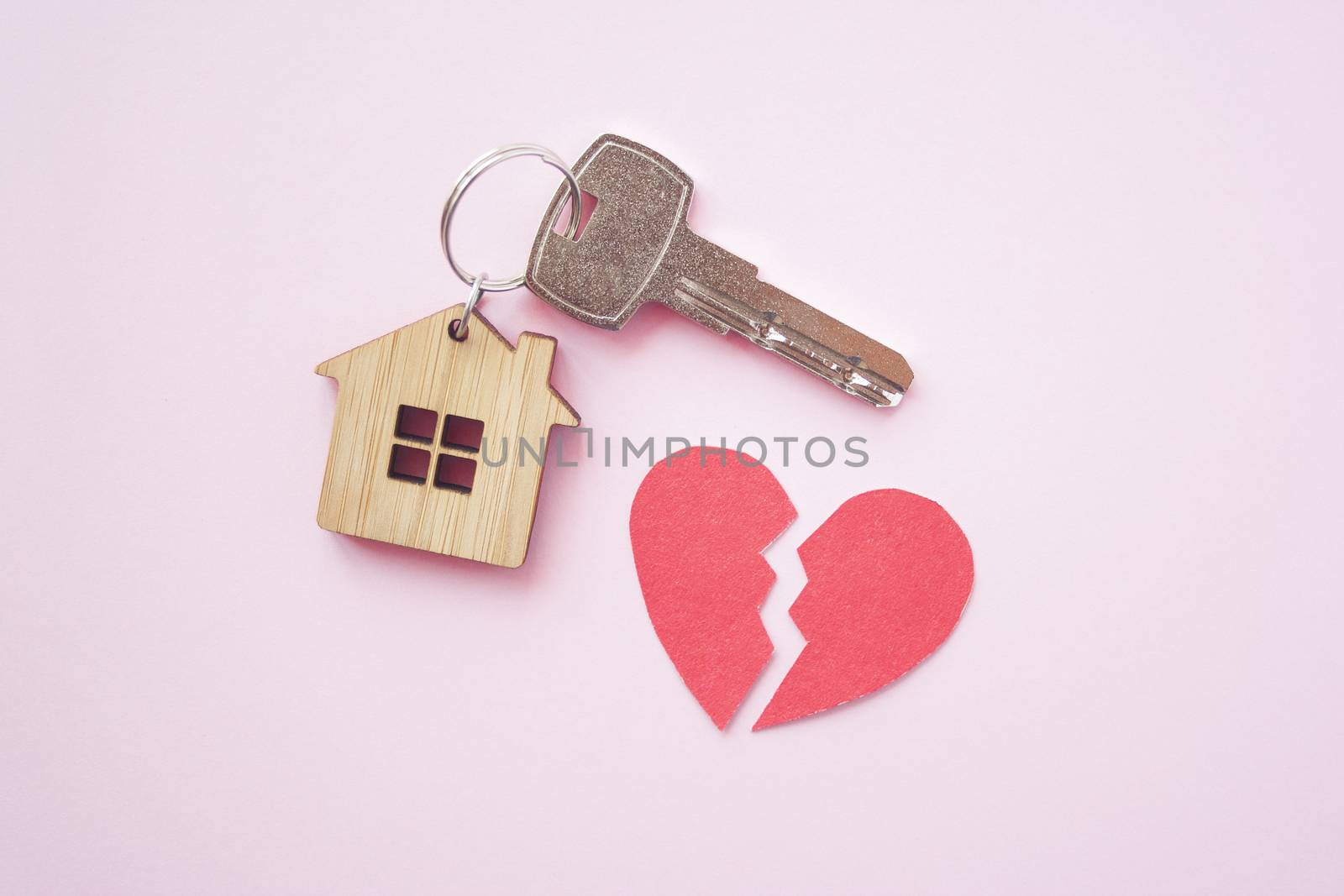 Wooden house toy and silver key with broken heart on bright pink background. Mortgage, house buy sell, investment, rent, realtor concept, cheating, problems and poverty concept