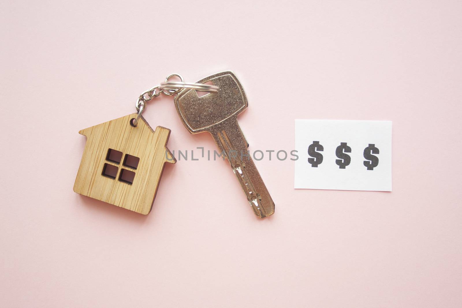 Wooden house toy and silver key on bright pink background with phrase quote $$$. Mortgage, house buy sell, investment, rent, realtor concept