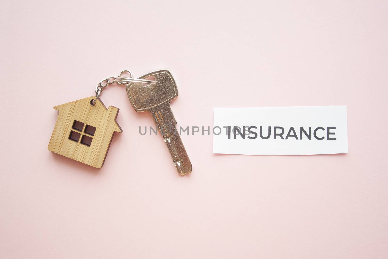 Wooden house toy and silver key on bright pink background with phrase quote Insurance. Mortgage, house buy sell, investment, rent, realtor concept