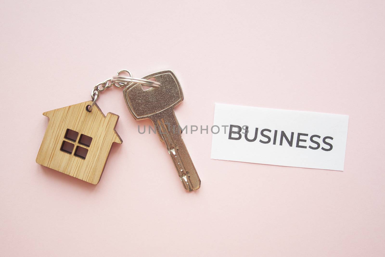 Wooden house toy and silver key on bright pink background with phrase quote business. Mortgage, house buy sell, investment, rent, realtor concept