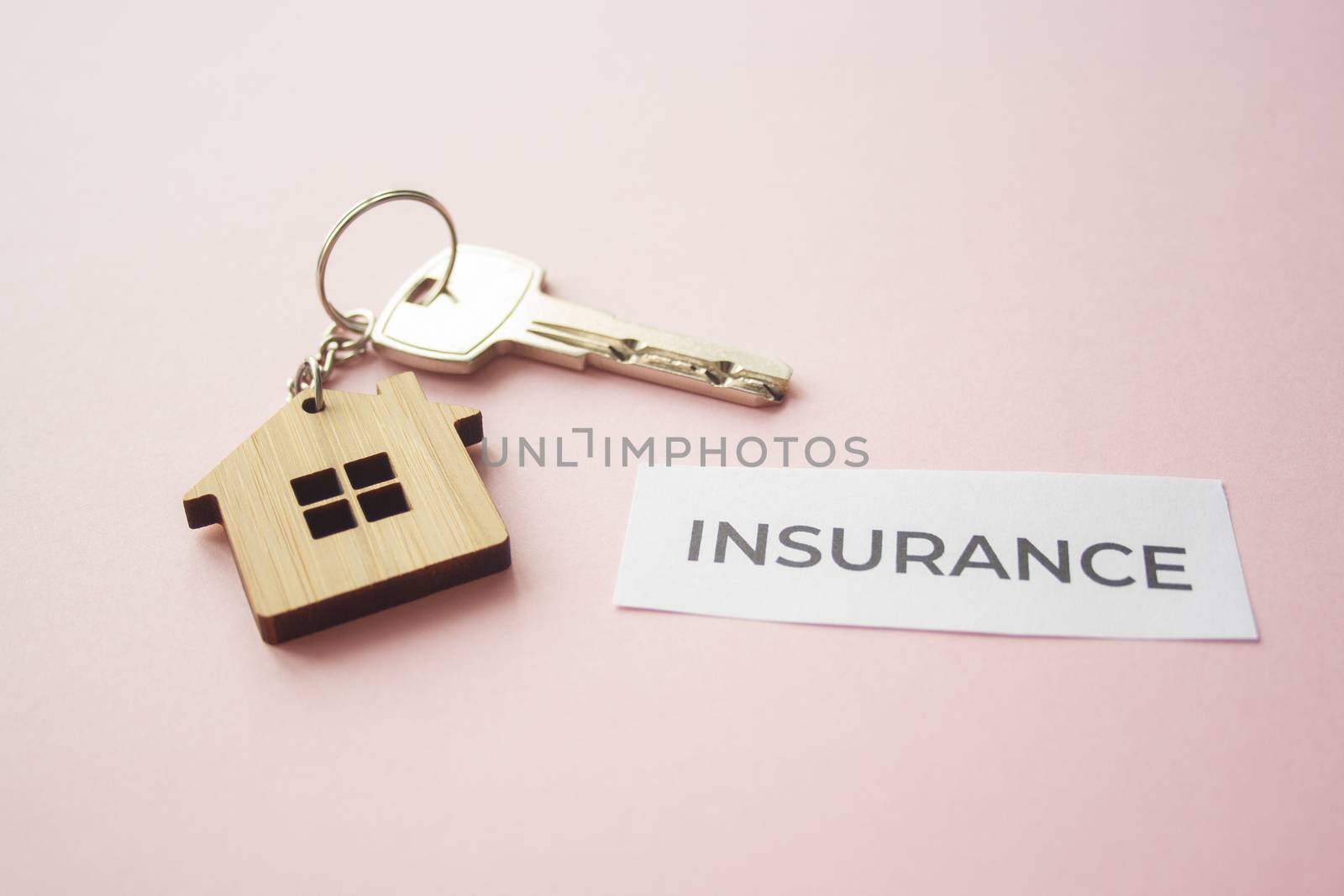 Wooden house toy and silver key on bright pink background with phrase quote Insurance. Mortgage, house buy sell, investment, rent, realtor concept