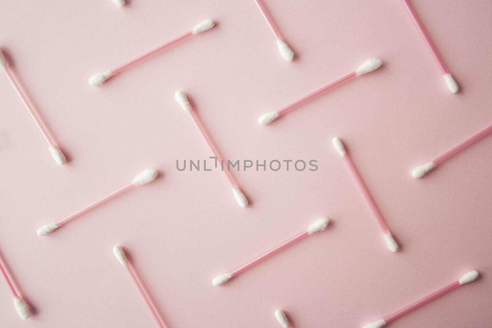 Flat lay cotton buds on pink warm background. Pattern of cotton swubs, beauty and health care concept. Cotton composition