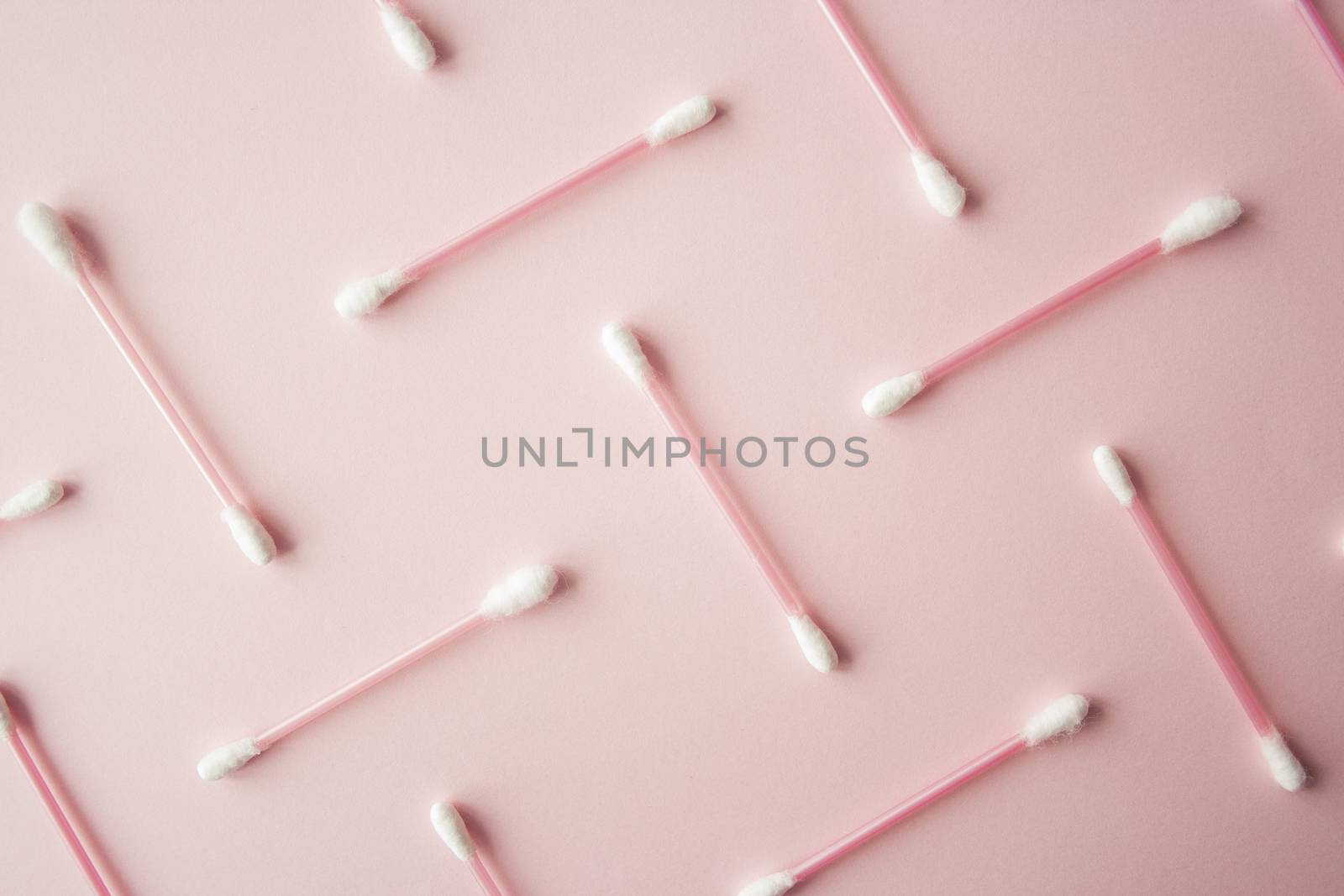 Flat lay cotton buds on pink warm background. Pattern of cotton swubs, beauty and health care concept. Cotton composition