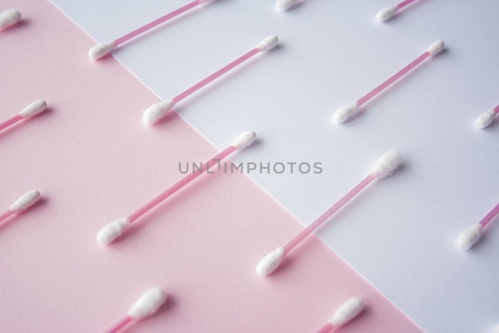 Flat lay cotton buds on pink warm and blue background. Pattern of cotton swubs, beauty and health care concept. Cotton composition