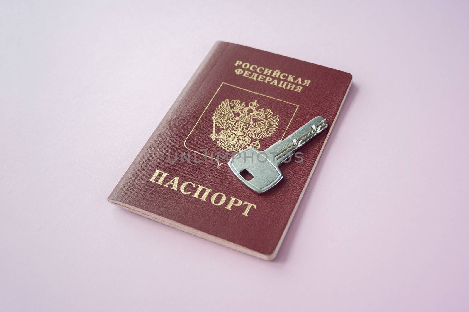 Russian international Passport and key  with trinket house on it on pink background close up copy space. Immigration, emigration, citizenship concept