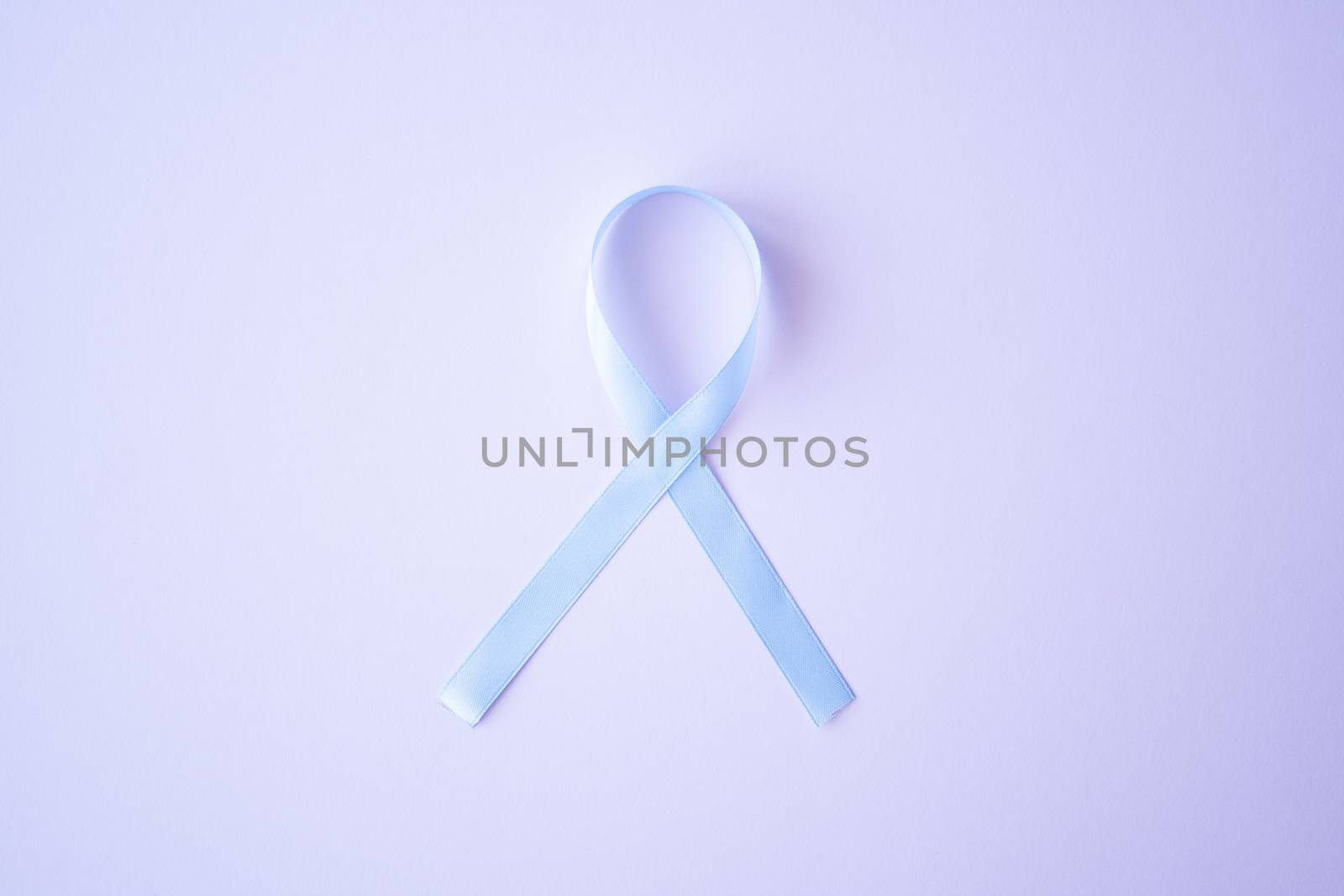 Prostate cancer awareness blue ribbon on pink background. Men healthcare concept, men carcinoma symbol.